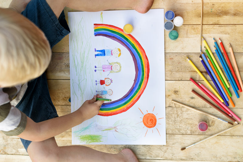 Child draws picture of family under rainbow.  Represents a gender inclusive family.